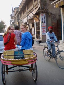 Two young women riding a cycle rickshaw in New Delhi, India